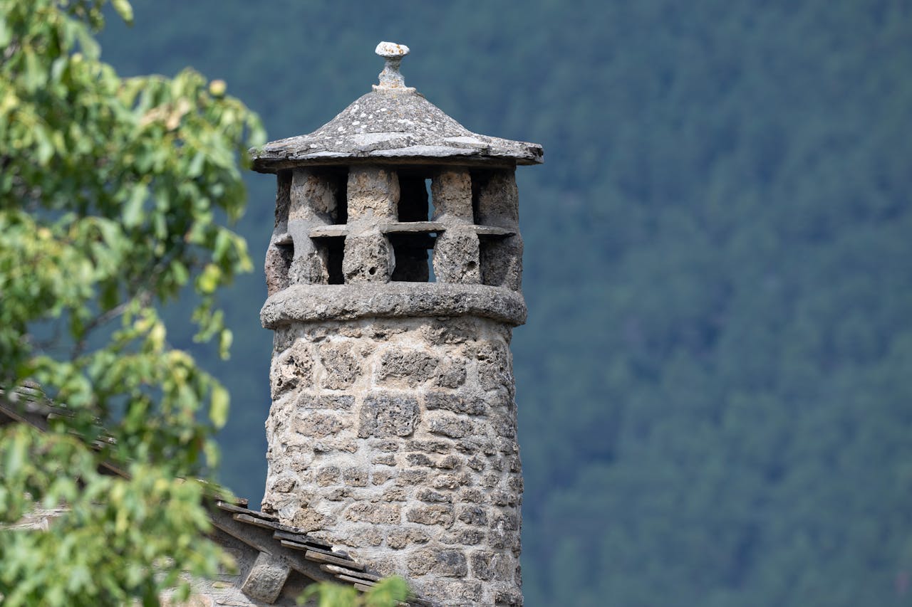 our-services-3 Close-up of a traditional stone chimney set against a forest backdrop in Huesca, Aragón, Spain.